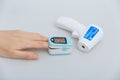 Pulse oximeter and thermometer gun on white background. Measuring oxygen saturation, pulse rate and oxygen levels