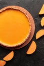 Pumkin pie on bamboo wood stand with cutted squash slices on black plaster background