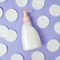 Pump cleansing lotion or liquid soap bottle and white cotton pads on blue purple background. Cosmetic packaging mockup, top view,