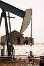 Pump jack near abandoned homestead Royalty Free Stock Photo