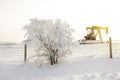 Pump jack in the sunrise light and the bush in snow in the oilfield Royalty Free Stock Photo