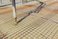 Pump tube is pouring concrete over quadratic reinforcing steel and plastic sewage pipes