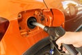 Pumping gasoline fuel in orange car at a gas station. Fill car with fuel in petrol station. Petrol station pump. Close up Royalty Free Stock Photo