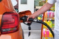 Pumping gasoline fuel in orange car at a gas station. To fill car with fuel in petrol station. Petrol station pump. Close up Royalty Free Stock Photo