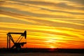 Pumpjack in the oil field at sunset