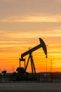 Pumpjack and transmission towers at sunset symbolizing energy transition