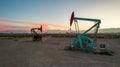 Pumpjack and transmission towers at sunset symbolizing energy transition. A pump jack pumping oil out of a well with silhouettes