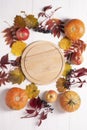 Pumpkin, apples, dry leaves, wild grapes lie on a white wooden background around a round board. Autumn composition. Autumn, fall, Royalty Free Stock Photo