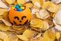 Pumpkin basket for Halloween, full of candy on the background of yellow fallen dry autumn leaves.