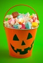 A Pumpkin Bucket Filled with Wrapped Saltwater Taffy on a Bright Green Background