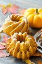 Pumpkin cakes with autumn leaves wooden background