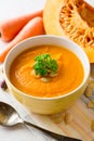 Pumpkin and carrot cream soup with pumpkin seeds and parsley in bowl on white wooden background. Royalty Free Stock Photo