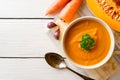 Pumpkin and carrot cream soup with pumpkin seeds and parsley in bowl on white wooden background. Royalty Free Stock Photo