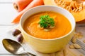 Pumpkin and carrot cream soup with pumpkin seeds and parsley in bowl on white wooden background. Royalty Free Stock Photo