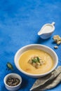 Pumpkin and carrot soup with cream and spinach with crackers on a classic blue background
