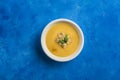 Pumpkin and carrot soup with cream and spinach with crackers on a classic blue background