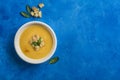 Pumpkin and carrot soup with cream and spinach with crackers on a classic blue background