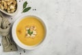 Pumpkin and carrot soup with cream and spinach with crackers on a white background