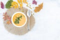 Pumpkin and carrot soup with pumpkin seeds and parsley in a white plate on white background with autumn leaves. Top view Royalty Free Stock Photo