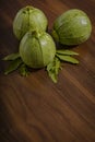 Composition of round pumpkins with epazote leaves on wooden table