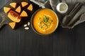 Pumpkin cream soup in a bowl with pumpkin seeds, parsley, cream and fresh orange butternut squash slices on wooden table. Traditio Royalty Free Stock Photo