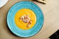 Creamy Delicious Pumkin Soup with fresh vegaetables over a wooden background