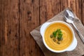 Pumpkin cream soup with a spoon on a wooden dark background