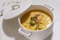 Pumpkin cream soup served with herbs in ceramic pot with lid Royalty Free Stock Photo