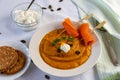 Pumpkin cream soup with whipped cream isolated on white blanket with salmon rolls on the wooden skewer. Royalty Free Stock Photo