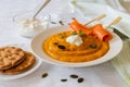 Pumpkin cream soup with whipped cream on white blanket with salmon rolls on the wooden skewer. Royalty Free Stock Photo
