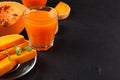 Pumpkin fresh juice in beautiful glasses and jug with pieces of ripe vegetable on brown wooden background. Sweet orange juice. Hea Royalty Free Stock Photo