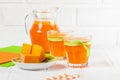 Pumpkin fresh juice in beautiful glasses and jug with pieces of ripe vegetable on white wooden background. Sweet orange juice. Hea Royalty Free Stock Photo