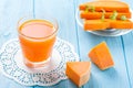 Pumpkin fresh juice in beautiful glasses and jug with pieces of ripe vegetable on white wooden background. Sweet orange juice. Hea Royalty Free Stock Photo