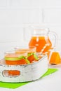 Pumpkin fresh juice in beautiful glasses and jug with pieces of ripe vegetable on white wooden background. Sweet orange juice. Hea Royalty Free Stock Photo