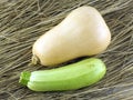 Pumpkin and green zucchini lying on dry hay