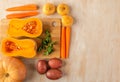 Pumpkin halves and a sprig of parsley on a bamboo cutting Board and other vegetables on a light wooden background