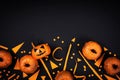 Pumpkin heads and confetti for Halloween party decor on black table top view. Flat lay style.