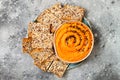 Pumpkin hummus seasoned with olive oil and black sesame seeds with whole grain crackers. Healthy vegetarian appetizer or snack.