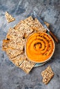 Pumpkin hummus seasoned with olive oil and black sesame seeds with whole grain crackers. Healthy vegetarian appetizer or snack.