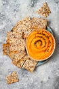 Pumpkin hummus seasoned with olive oil and black sesame seeds with whole grain crackers. Healthy vegetarian appetizer or snack.