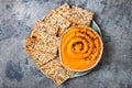 Pumpkin hummus seasoned with olive oil and black sesame seeds with whole grain crackers. Healthy vegetarian appetizer or snack.