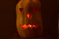 A pumpkin lantern of a fabulous monster with glowing eyes looks out from the darkness