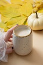 Pumpkin latte in female hand. Warm autumn drink concept