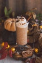 Pumpkin latte in high transparent glass with froth of whipped cream sprinkled with chocolate and cinnamon