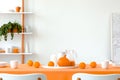 Pumpkin, oranges, mugs and jars on the dining room table covered with orange tablecloth. White empty wall with copy space Royalty Free Stock Photo