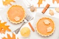 Pumpkin pie with cinnamon and cookies on gray napkins on white wooden background with autumn yellow leaves. Royalty Free Stock Photo
