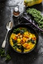 Pumpkin, potatoes, beans and kale stewed vegetarian autumn lunch on a dark background, top view