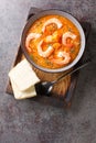 Pumpkin puree soup with shrimp, sesame and thyme served with bread on a wooden tray. Vertical top view