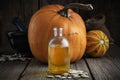 Pumpkin seeds oil bottle closeup, two pumpkins, bag of seeds and mortar on background.