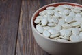 Pumpkin seeds in a plate. Dark wooden background. Copy space